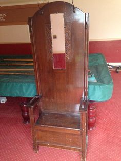 an old wooden chair sitting on top of a red carpeted floor next to a bed