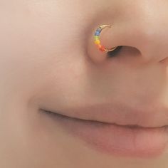 a close up of a person's nose with a rainbow colored ring on it