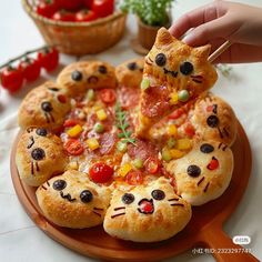 a person is holding a piece of pizza with cats on it and some tomatoes in the background