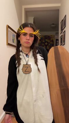 a woman with long hair wearing a white shirt and yellow crown holding a surfboard