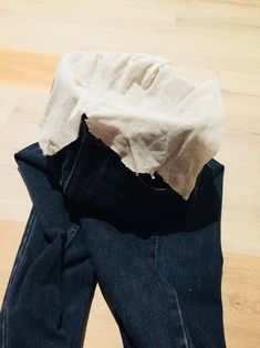 a pair of jeans that are sitting on top of a wooden floor with a piece of cloth sticking out of it