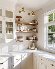 a kitchen filled with lots of white cabinets and counter top space next to a window