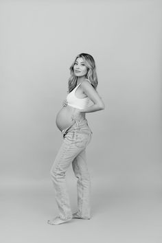 a pregnant woman poses for a black and white photo with her belly exposed in jeans