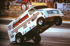 a car that is upside down in the air with people watching from the stands behind it