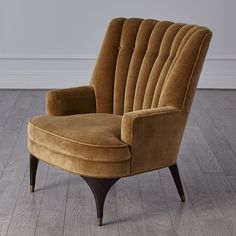 a brown chair sitting on top of a hard wood floor next to a white wall