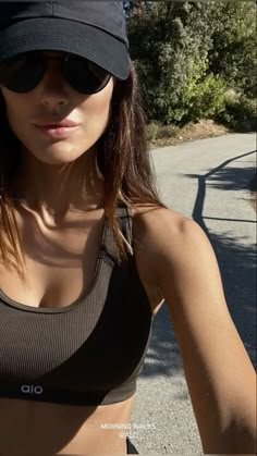 a woman wearing a hat and sunglasses is posing for the camera with her hand on her hip