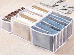 four pairs of jeans hanging in an organized storage bin on the floor next to clothes