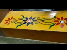 a yellow box with flowers painted on it