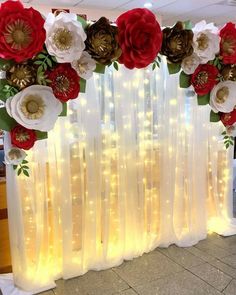 an arrangement of paper flowers and lights in front of a curtain