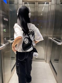 a woman with long black hair wearing headphones standing in front of a glass door