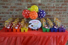 a table topped with lots of colorful balloons and candy bar wrappers on top of it