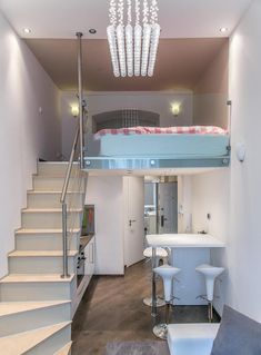 a living room filled with furniture and a loft bed above the stairs next to a kitchen