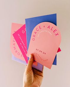 a person holding up some pink and blue cards with the words grace and alex on them