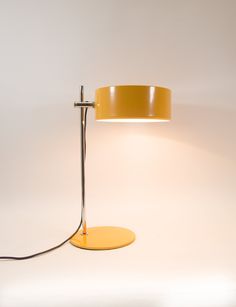 a yellow lamp on a white background with a black cord attached to the light fixture