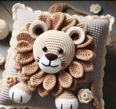 a crocheted lion pillow sitting on top of a wooden floor next to flowers