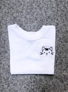 a white t - shirt with a black cat embroidered on it