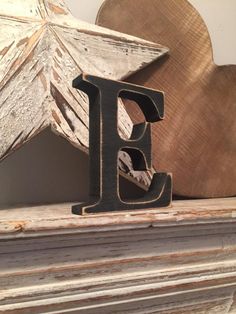 a wooden letter sitting on top of a mantle next to a star shaped wood object