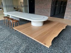 a large white table sitting in the middle of a room with stools around it