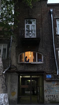 two people sitting in the window of an old building