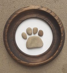 a wooden frame with rocks in it and a paw print on the inside of it