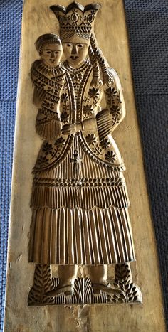 an intricately carved wooden plaque depicting two women in traditional garb, with one holding a child