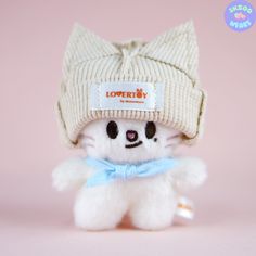 a small white teddy bear wearing a knitted hat and blue bow tie on it's head