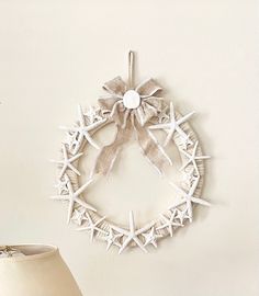 a starfish wreath is hanging on the wall next to a lamp and a vase