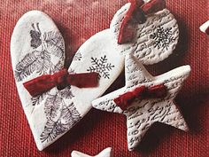 three heart shaped cookies decorated with red bows and snowflakes on a red tablecloth