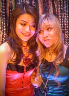 two young women standing next to each other in front of beaded curtained background