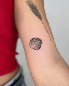 a woman's arm with a shell and feather tattoo on the left side of her arm