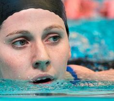 a woman swimming in a pool with her eyes open and water droplets on her face