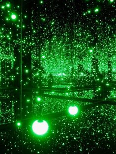 green lights are shining in the dark with balls on the floor and behind them is a mirror