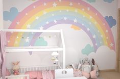 a child's room decorated in pastel colors with rainbows and stars on the wall