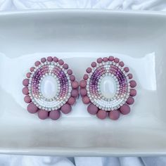 These earrings are meticulously handcrafted with quality Japanese seed beads in cream, beige, pink & purple with opal rhinestone banding edged with mauve beads on a silver nickel-free stud post. Earring backing is faux leather. Earrings measure ~1 3/4" wide and ~2" in length. Cab Earrings, Fancy Shawl Regalia, Purple Beaded Earrings, Pink Beaded Earrings, Beaded Stud Earrings, Fancy Shawl, Beadwork Ideas, Beading Inspiration, Native Beadwork