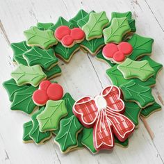 decorated christmas cookies arranged in the shape of a wreath with holly leaves and bows on top