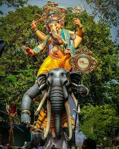 an elephant statue with a man riding on it's back in front of trees