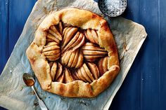 an apple pie on a piece of parchment paper next to a spoon and salt shaker