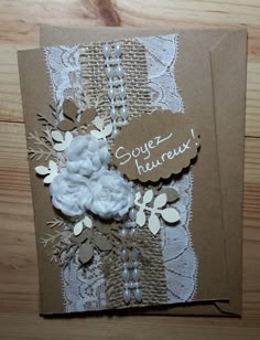 a close up of a greeting card with flowers and doily on wood table top