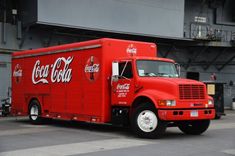 a red coca cola truck parked in front of a building