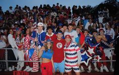 a group of people standing next to each other in front of a crowd with american flags