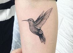 a small hummingbird tattoo on the arm