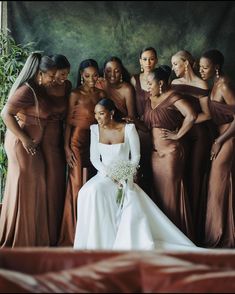 a group of women standing next to each other in front of a green wall wearing brown dresses