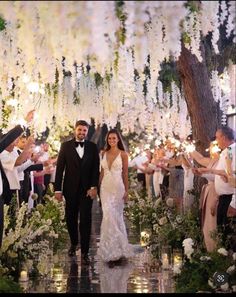 a bride and groom walk down the aisle at their wedding ceremony with guests holding sparklers