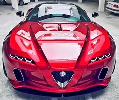 the front end of a red sports car parked in a parking lot with other cars