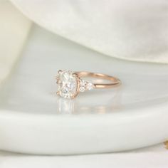 a close up of a diamond ring on a white plate with a cloth in the background