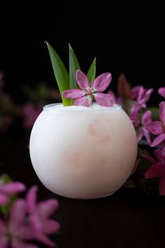 a white vase filled with purple flowers on top of a table