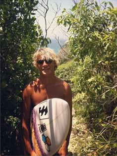 a man holding a surfboard in the woods