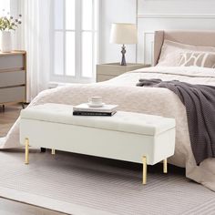 a bedroom with a bed, nightstands and a white bench on the floor in front of it