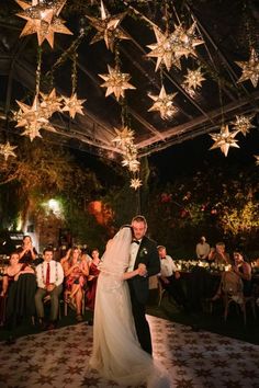 a bride and groom are dancing under stars