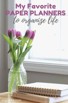 a vase filled with purple tulips sitting on top of a table next to a book